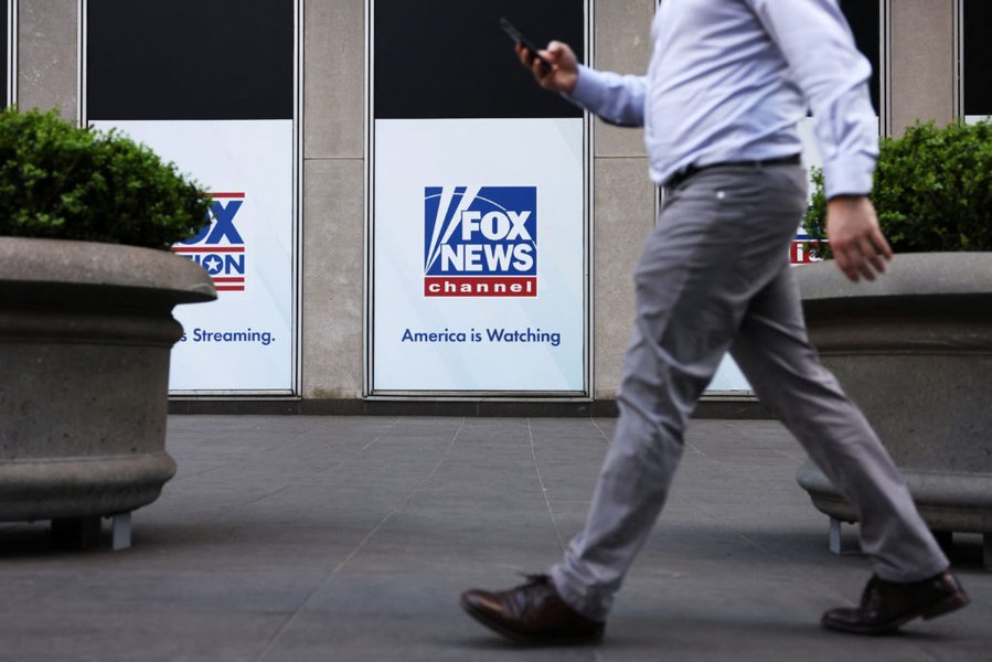A person walks by Fox News signage posted on the News Corporation building in New York City