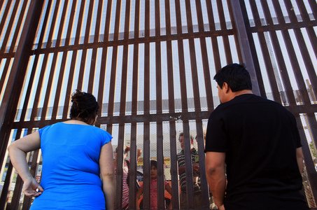 Betcy and Marco Cruz talk with family members at the fence separating the United States and Mexico in downtown Calexico, California