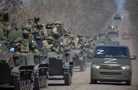 Service members of pro-Russian troops ride on armoured vehicles on a road leading to Mariupol