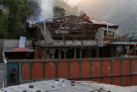 A Pakistan Army soldier stands guard at the entrance, as smoke rises from the Bilal Mosque after it was hit by an Indian strike in Muzaffarabad